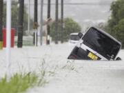 A vehicle is stuck on a street flooded due to a heavy rain in Kurume, Fukuoka prefecture, southern Japan Monday, July 10, 2023. Torrential rain is pounding southwestern Japan, triggering floods and mudslides Monday as weather officials issued emergency heavy rain warning in parts of on the southern most main island of Kyushu.