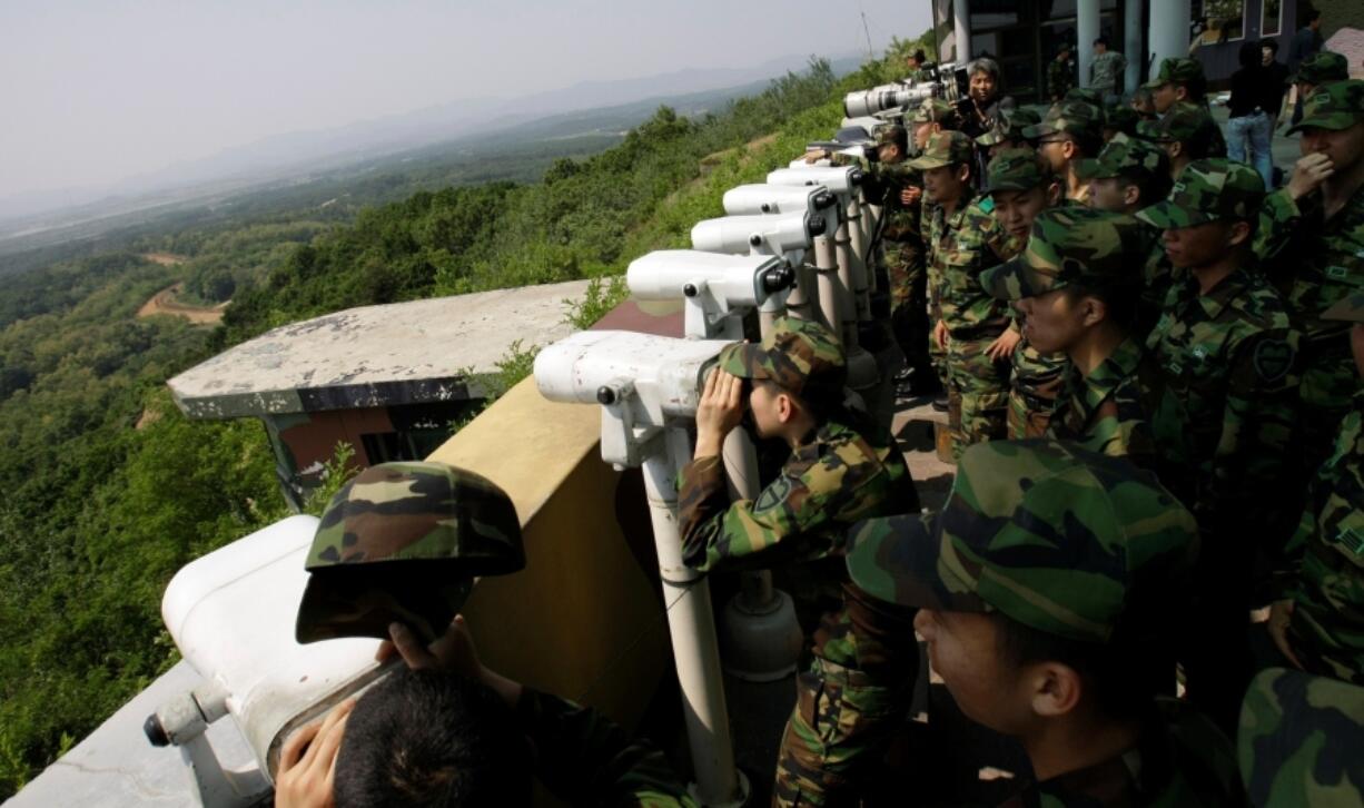 FILE - South Korean soldiers look at the North Korean side through binoculars at Dora Observation Post in the demilitarized zone, DMZ, near the border village of Panmunjom that separates the two Koreas since the Korean War, in Paju, north of Seoul, South Korea, Wednesday, May 27, 2009. A series of low-slung buildings and somber soldiers dot the landscape of the DMZ, the swath of land between North and South Korea where a soldier on a tour crossed into North Korea on Tuesday, July 18, 2023, under circumstances that remain unclear.