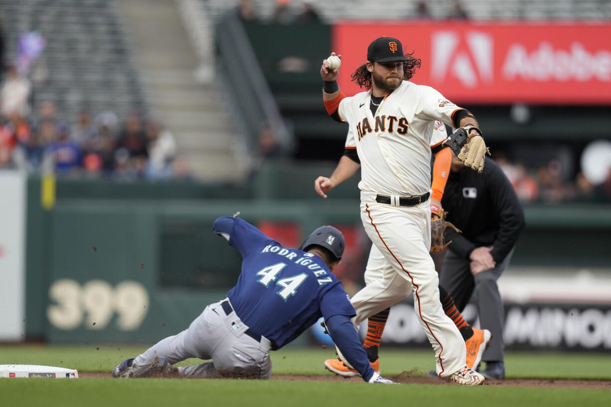 San Francisco Giants shortstop Brandon Crawford turns a double play as the Seattle Mariners' Julio Rodriguez (44) is forced out at second base in the first inning of a baseball game in San Francisco, Wednesday, July 5, 2023. The Mariners' Teoscar Hernandez was out at first base on the play.