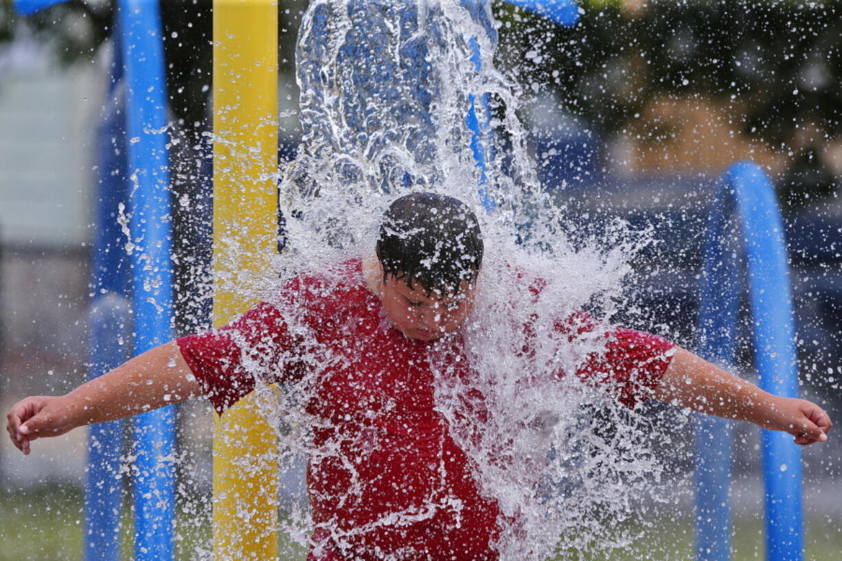 Graiden Therrien, 11, cools off in a water feature Monday at Harrington Park in New Bedford, Mass., amid sweltering heat.