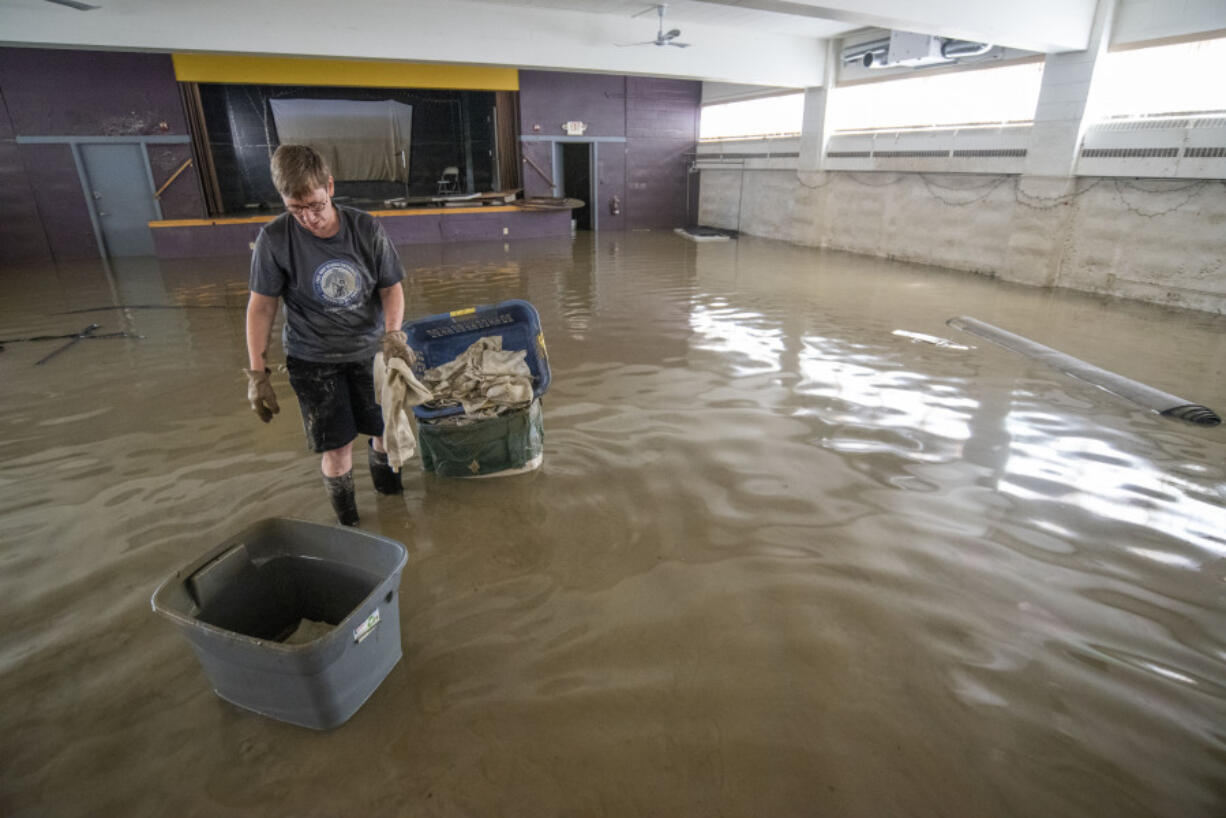 Congregation member Gayle McFarland, of Montpelier, Vt., collects sodden table cloths in the basement of Bethany Church, in downtown Montpelier, Thursday, July 13, 2023. In Vermont, communities were cleaning up Thursday from the floods that were more destructive in some places than 2011's Tropical Storm Irene.