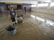 Congregation member Gayle McFarland, of Montpelier, Vt., collects sodden table cloths in the basement of Bethany Church, in downtown Montpelier, Thursday, July 13, 2023. In Vermont, communities were cleaning up Thursday from the floods that were more destructive in some places than 2011's Tropical Storm Irene.