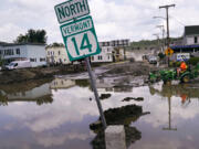 A small tractor clears water from a business as flood waters block a street, Wednesday, July 12, 2023, in Barre, Vt. Following a storm that dumped nearly two months of rain in two days, Vermonters are cleaning up from the deluge of water.