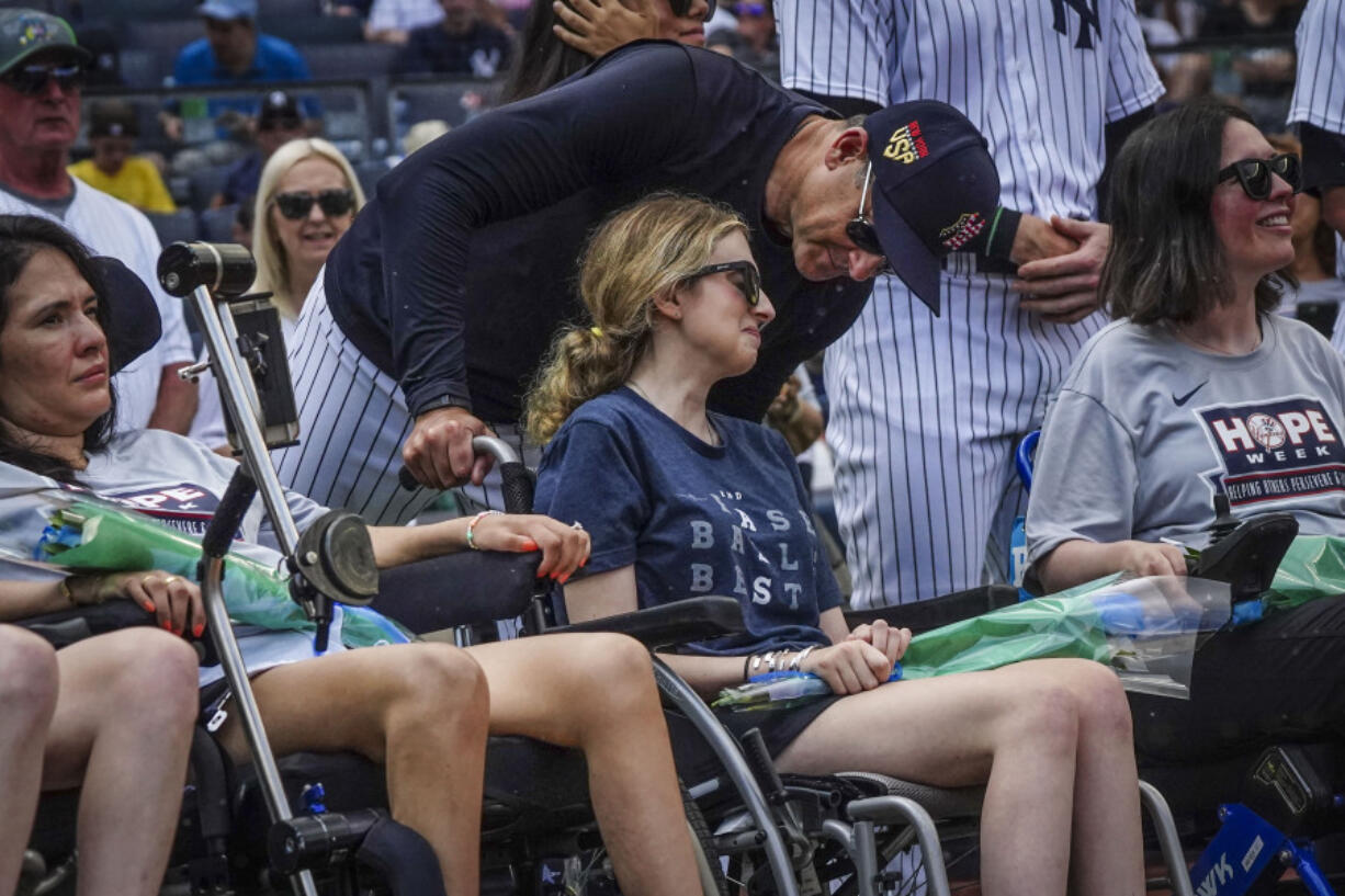 New York Yankees manager Aaron Boone, center, talk with Sarah Langs, their HOPE Week honoree, on the 84th anniversary of Lou Gehrig making his famous "Luckiest Man" speech, Tuesday, July 4, 2023, in New York. Langs, one of Major League Baseball's most respected and universally liked statistical analysts, has been in a battle with ALS the last three years. Langs and women from the organization "Her ALS Story" made a pregame tour of Monument Park and the Yankees Museum.