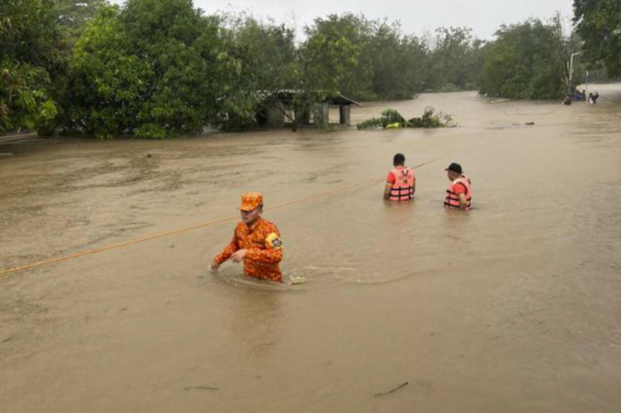 In this photo provided by the Philippine Coast Guard, rescuers wade along floodwaters caused by Typhoon Doksuri as they search for residents to evacuate to higher grounds in Bacarra, Ilocos Norte province, northern Philippines on Wednesday July 26, 2023. Typhoon Doksuri ripped off tin roofs from homes, engulfed low-lying villages in flood, knocked down power and displaced more than 12,000 people Wednesday as it smashed into a small island and lashed northern Philippine provinces overnight with ferocious wind and rain, officials said.