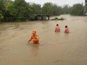 In this photo provided by the Philippine Coast Guard, rescuers wade along floodwaters caused by Typhoon Doksuri as they search for residents to evacuate to higher grounds in Bacarra, Ilocos Norte province, northern Philippines on Wednesday July 26, 2023. Typhoon Doksuri ripped off tin roofs from homes, engulfed low-lying villages in flood, knocked down power and displaced more than 12,000 people Wednesday as it smashed into a small island and lashed northern Philippine provinces overnight with ferocious wind and rain, officials said.