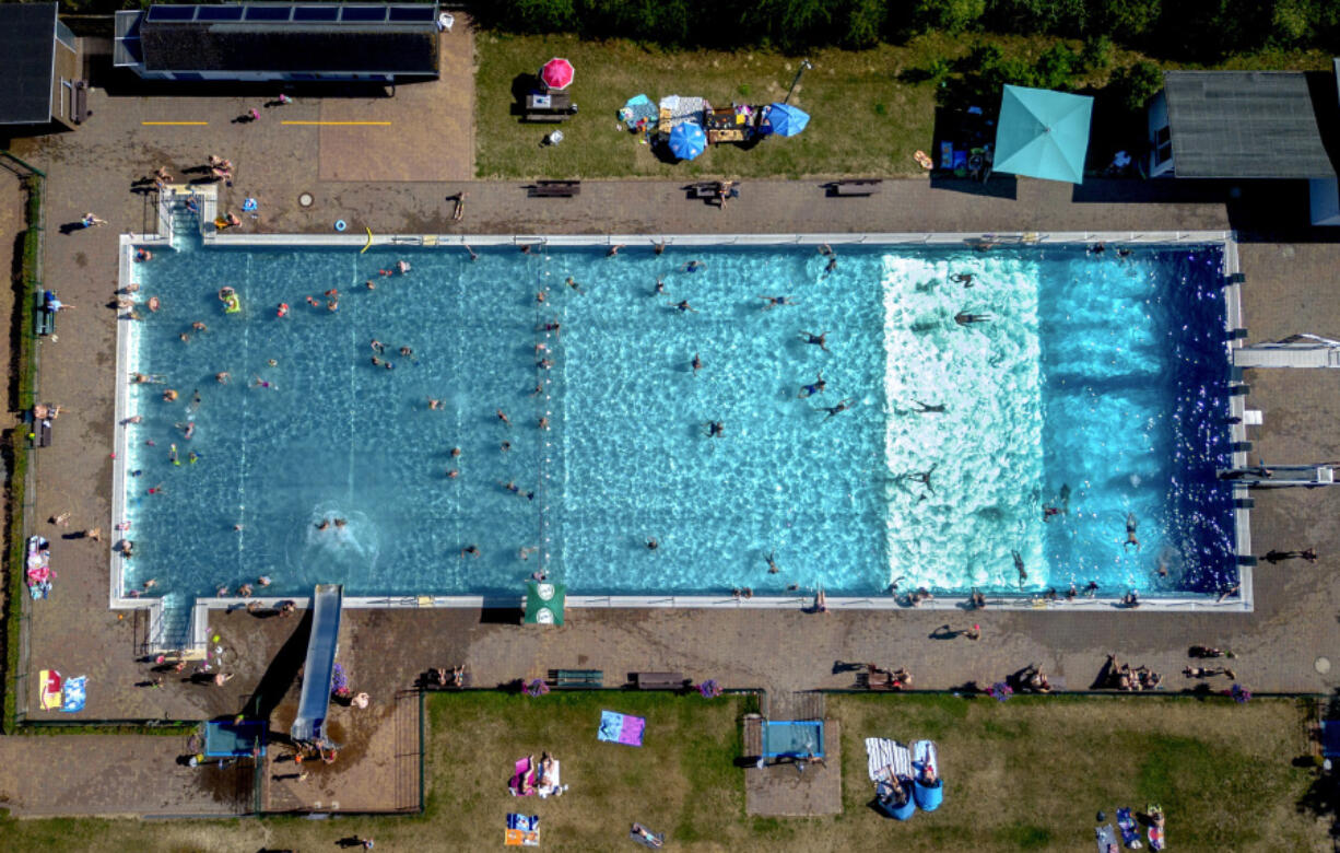 People spend time in a public pool in Wehrheim near Frankfurt, Germany, on a hot Saturday, July 8, 2023.