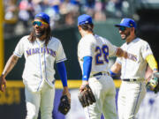 Seattle Mariners shortstop J.P. Crawford smiles with teammates third baseman Eugenio Suarez and second baseman Jose Caballero, right, as they celebrate their win over the Tampa Bay Rays after a baseball game, Sunday, July 2, 2023, in Seattle.