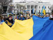 FILE - Demonstrators hold a Ukrainian flag as they march outside of the White House in support of Ukraine during a rally in Washington, Feb. 25, 2023. One of the architects of the covert U.S. strategy against the Soviets in Afghanistan has published a new memoir. In "By All Means Available," Michael Vickers calls on President Joe Biden's administration to increase its support for Ukraine's resistance against Russia.