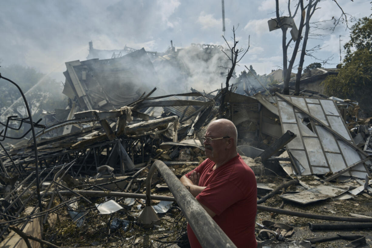 A man watches as emergency service personnel work at the site of a destroyed building after a Russian attack in Odesa, Ukraine, Thursday, July 20, 2023. Russia pounded Ukraine's southern cities, including the port city of Odesa, with drones and missiles for a third consecutive night in a wave of strikes that has destroyed some of the country's critical grain export infrastructure.