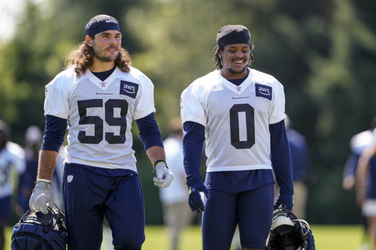 Seattle Seahawks linebacker Jon Rhattigan (59) walks with linebacker Devin Bush (0) during the NFL football team's training camp, Thursday, July 27, 2023, in Renton, Wash.