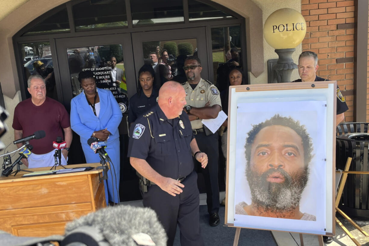 In this photo tweeted by WSB-TV's Steve Gehlbach, Hampton Police Chief James Turner, center, stands next to a mounted picture of suspect Andre Longmore during a news conference in Hampton, Ga., Saturday, July 15, 2023. Authorities are searching for Longmore, who is suspected of gunning down three men and a woman in Hampton.