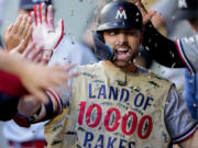 Minnesota Twins' Edouard Julien wears a fishing vest in the dugout as teammates throw sunflower seeds at him to celebrate his solo home run against the Seattle Mariners during the fifth inning of a baseball game, Wednesday, July 19, 2023, in Seattle.