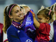 FILE -United States' Alex Morgan holds her daughter, Charlie, as she listens to Cindy Parlow Cone, president of the U.S. Soccer Federation, speak during an event with the federation, U.S. Women's National Team Players Association and the U.S. National Soccer Team Players Association at Audi Field in Washington, Tuesday, Sept. 6, 2022. Morgan says she feels calmer heading into this World Cup and wants to represent mom athletes. She's one of three mothers on this U.S. squad and is often accompanied by 3-year-old daughter Charlie.