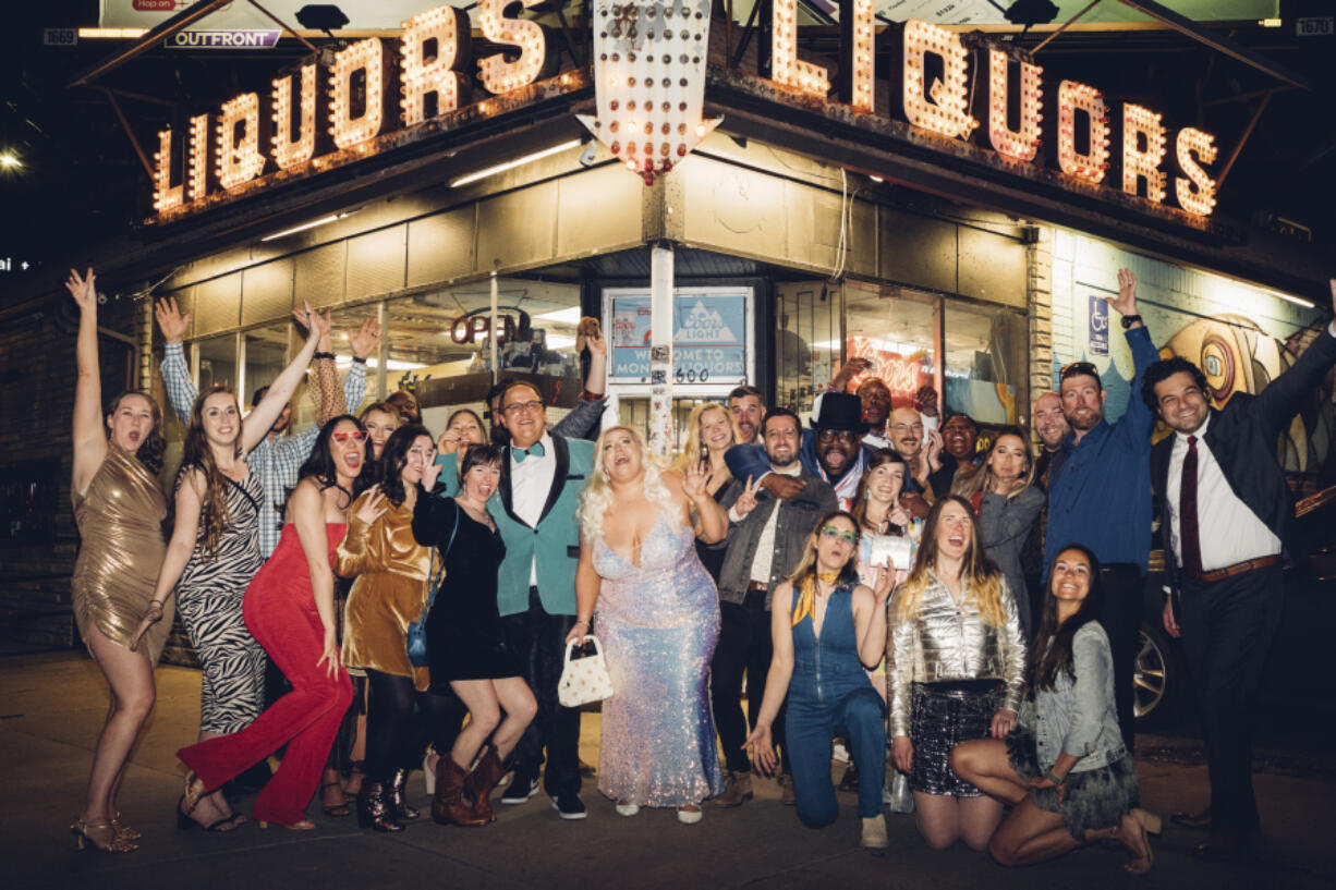 Wedding guest Maggie Long, left, poses in a group photo April 1 with others including groom Travis Holquin, in green tux center left, and bride Hannah Holquin, silver gown in center, at a dive bar-themed wedding in Denver. More than ever, wedding guests are contending with nontraditional dress code requests.