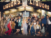 Wedding guest Maggie Long, left, poses in a group photo April 1 with others including groom Travis Holquin, in green tux center left, and bride Hannah Holquin, silver gown in center, at a dive bar-themed wedding in Denver. More than ever, wedding guests are contending with nontraditional dress code requests.