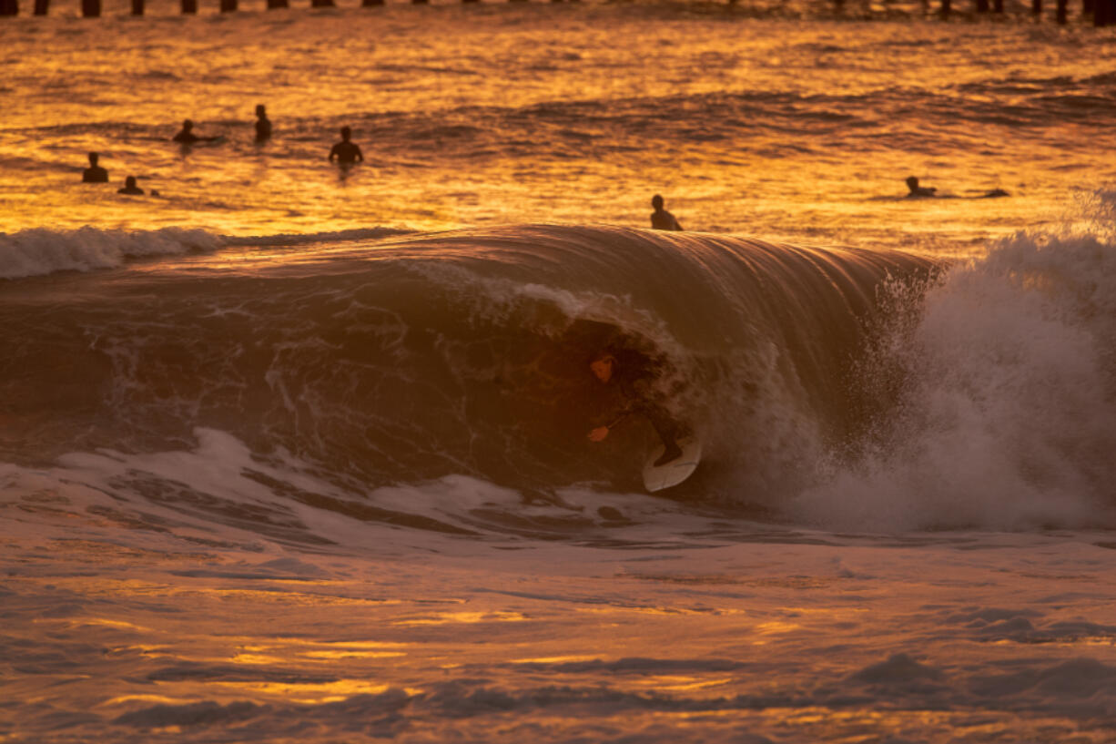 With the golden glow of the sunset, surfer Dylan Sloan, 15, of Huntington Beach, California, gets a coveted tube ride  the Seal Beach pier. (Allen J.