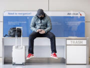 An American Airlines passenger listens to a conference call Feb. 23 as he waits for his flight in Terminal A at DFW Airport in Dallas.