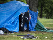 A Minneapolis Police officer checks a structure July 20, 2020, in Powderhorn Park before clearing it to be destroyed as a homeless encampment is cleared on in Minneapolis, Minn.