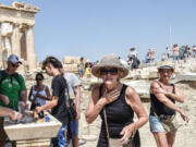 Tourists refresh with water in front of the 5th century B.C. Parthenon temple at the Acropolis hill during a heat wave on July 20 in Athens, Greece.