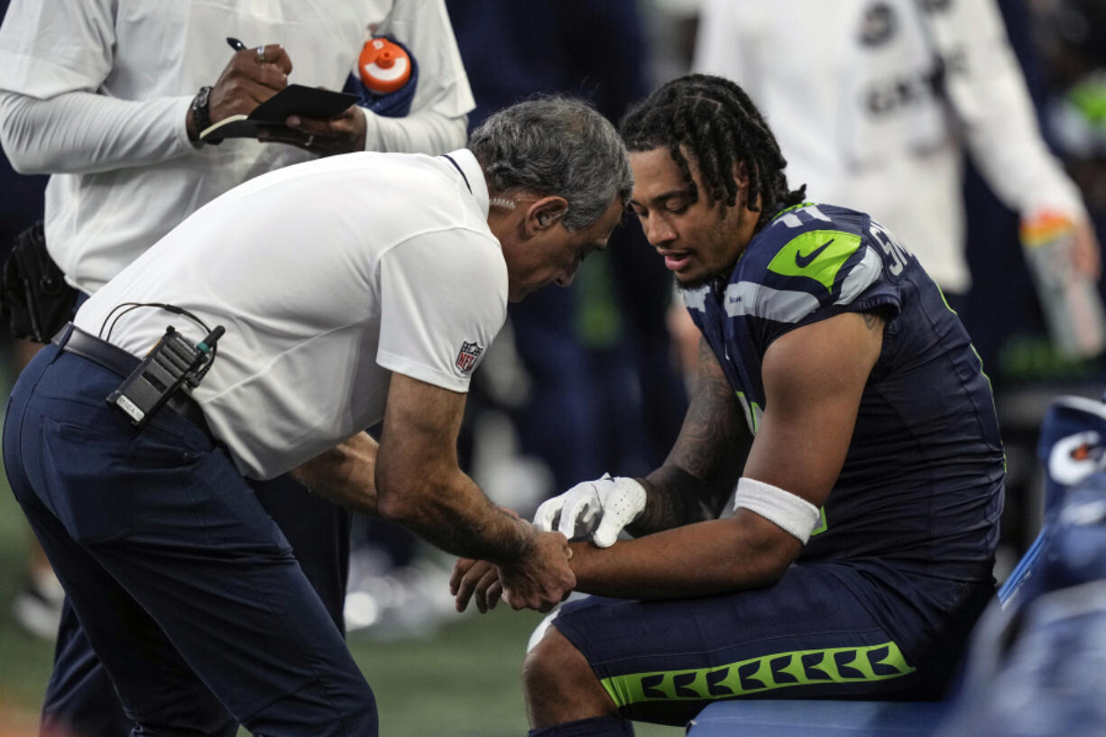 Seattle Seahawks team personnel check out the wrist of wide receiver Jaxon Smith-Njigba during an NFL preseason football game against the Dallas Cowboys, Saturday, Aug. 19, 2023, in Seattle. The Seahawks won 22-14.