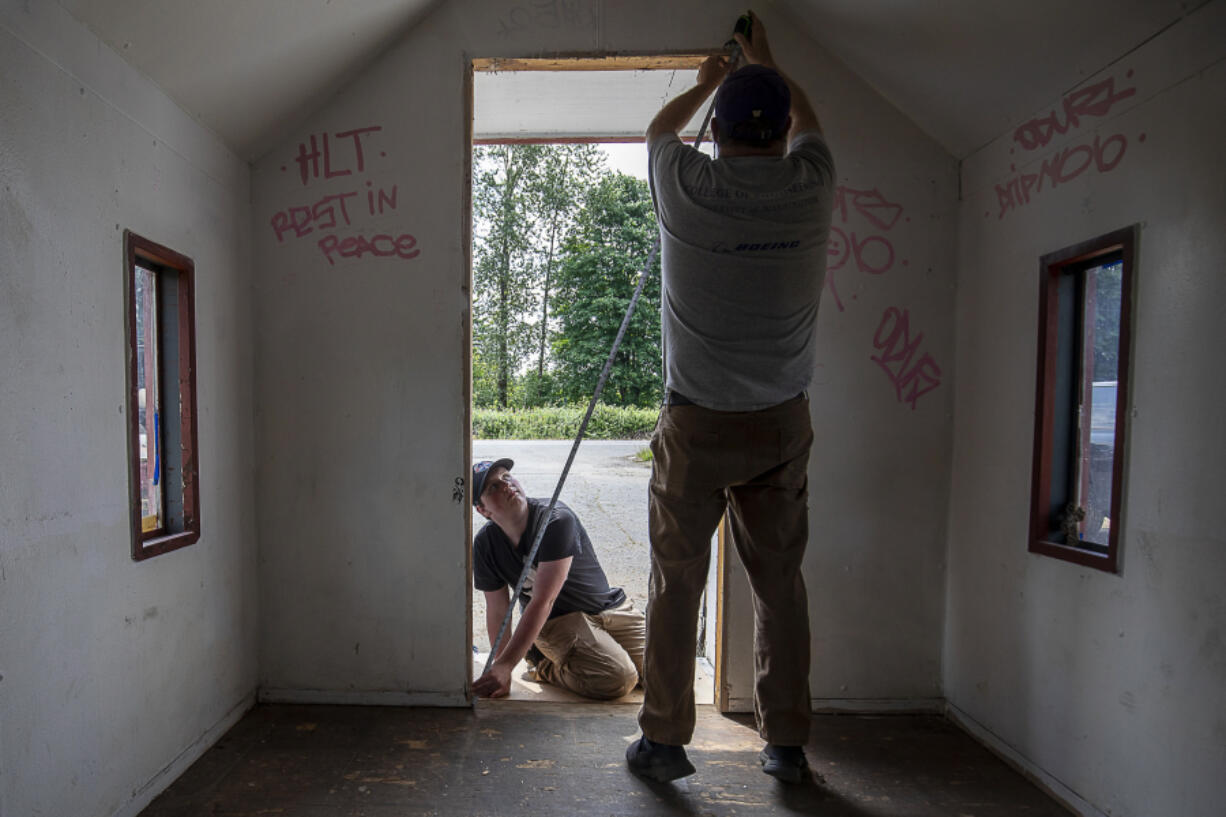 Michael Durkee, 15, left, holds a tape measure for Jeffrey Forbes, 60, at the Wayside Chapel along U.S. 2 in Monroe on June 24. Michael is leading the effort for his Eagle Scout project.