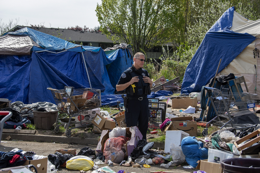 Vancouver Police Department officer Tyler Chavers chats with residents of a homeless encampment in northeast Vancouver in April 2021.