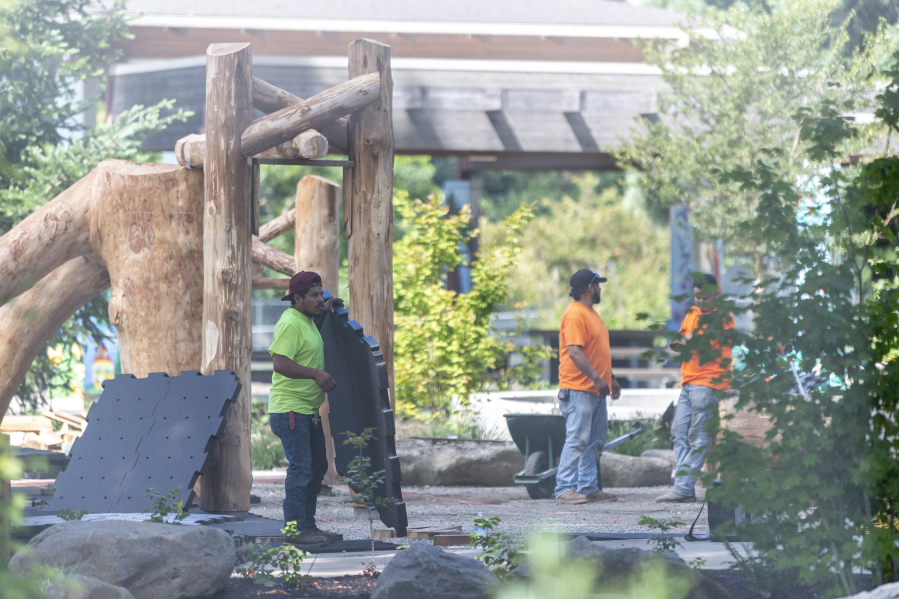 Workers install an artificial turf surface at Marshall Park. Though more expensive than wood chips, disability advocates say plastic turf is a key to making playgrounds more accessible.