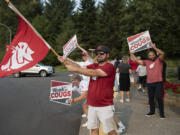 Jack Fisher, 15, from left, joins his brother, Will, 13, with maroon hat, their dad, P.J., black hat, who is a Washington State University alum, and Narek Daniyelyan, right, who is also an alum, as they greet students and staff on the first day of classes at Washington State University Vancouver on Monday morning (Amanda Cowan/The Columbian)