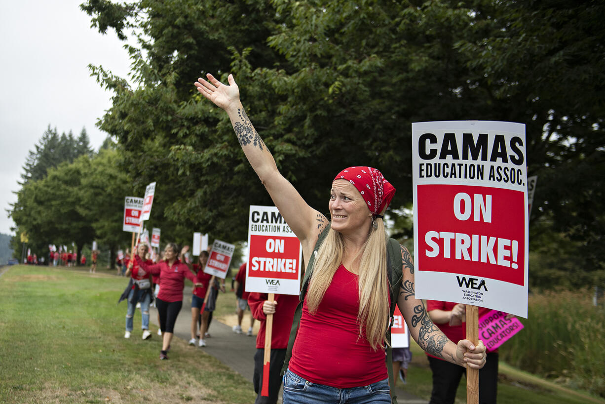 Camas High School teacher Ruhiyyih Wittwer, cq, red scarf, greets a motorist as she joins fellow educators and supporters during a district wide strike outside Camas High School on Monday morning, Aug. 28, 2023. The strike postponed the first day of school in the district.