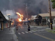 CORRECTS DATE TO AUG. 8 - People watch as smoke and flames fill the air from raging wildfires on Front Street in downtown Lahaina, Maui on Tuesday, Aug. 8, 2023. Maui officials say wildfire in the historic town has burned parts of one of the most popular tourist areas in Hawaii. County of Maui spokesperson Mahina Martin said in a phone interview early Wednesday says fire was widespread in Lahaina, including Front Street, an area of the town popular with tourists.