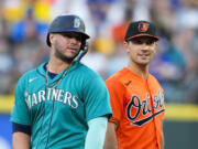 Seattle Mariners' Ty France, left, talks with former teammate Baltimore Orioles second baseman Adam Frazier during the fourth inning of a baseball game, Saturday, Aug. 12, 2023, in Seattle.