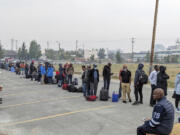 People without vehicles lineup to register for a flight to Calgary, Alberta in Yellowknife on Thursday, Aug. 17, 2023. Prime Minister Justin Trudeau is expected to convene an urgent meeting with ministers and senior officials today as residents of the capital of Northwest Territories are ordered to evacuate the area because of an encroaching wildfire.