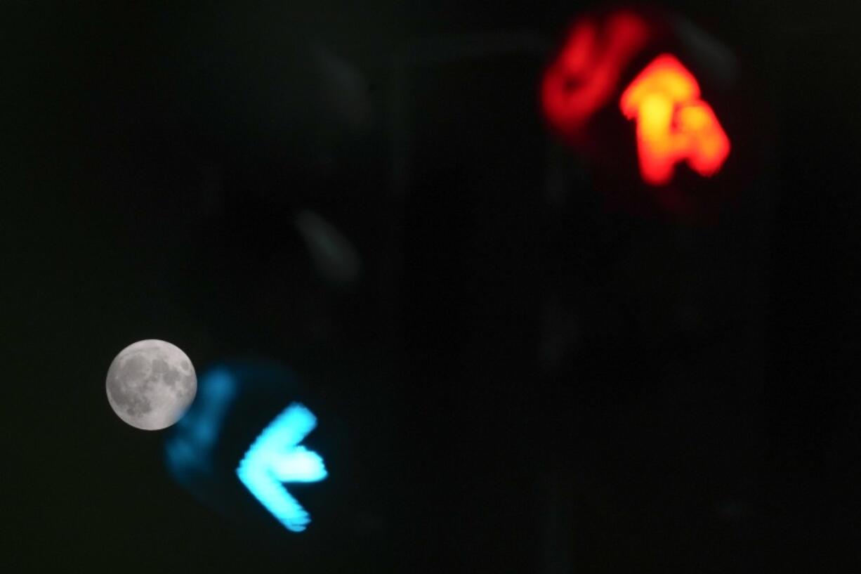 A supermoon is framed by the lights of a semaphore in Rome, Wednesday, Aug. 30, 2023.