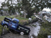 Pick up trucks and debris lie strewn in a canal in Horseshoe Beach, Fla., after the passage of Hurricane Idalia, Wednesday, Aug. 30, 2023.