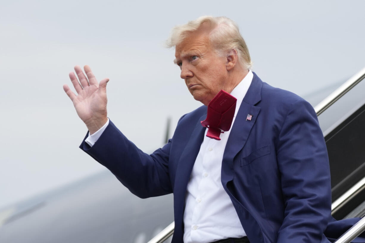 FILE - Former President Donald Trump waves as he steps off his plane at Ronald Reagan Washington National Airport, Aug. 3, 2023, in Arlington, Va. A slim majority of Americans approve of the U.S. Justice Department indicting Trump over his efforts to remain in office after losing the 2020 election, according to a new poll from The Associated Press-NORC Center for Public Affairs Research.