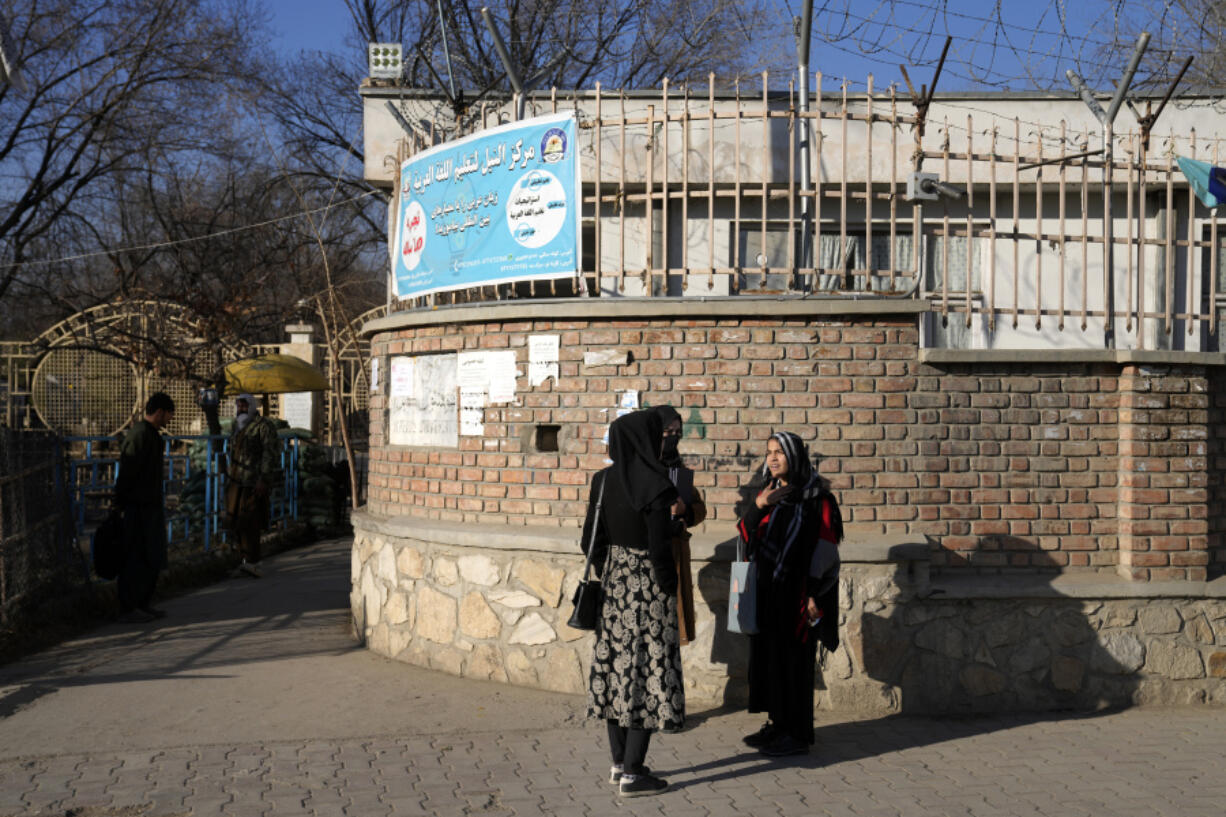 FILE - Afghan women students stand outside the Kabul University in Kabul, Afghanistan, Wednesday, Dec. 21, 2022. Afghanistan's higher education minister Nida Mohammed Nadim on Saturday, Aug. 12, 2023, says universities are ready to welcome back female students but the Taliban supreme leader has to give the order for their return. The Taliban barred women from campuses last December, triggering global outrage.