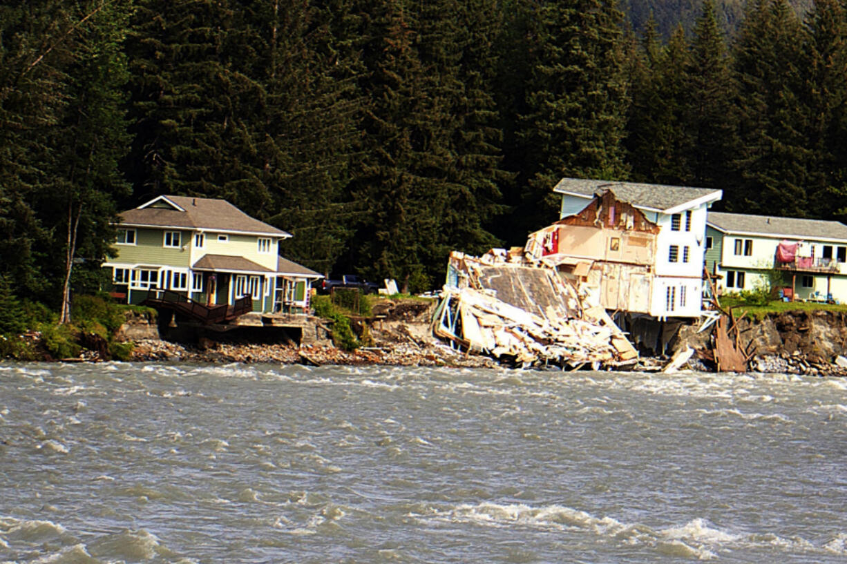 A home hangs over the edge of an eroded riverbank after part of the neighboring house fell into the Mendenhall River in Juneau, Alaska, on Sunday. The city of Juneau says the Mendenhall River flooded on Saturday because of a major release from Suicide Basin above Alaska's capital city, and at least two buildings were destroyed.