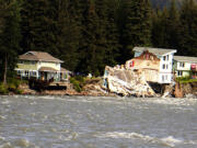 A home hangs over the edge of an eroded riverbank after part of the neighboring house fell into the Mendenhall River in Juneau, Alaska, on Sunday. The city of Juneau says the Mendenhall River flooded on Saturday because of a major release from Suicide Basin above Alaska's capital city, and at least two buildings were destroyed.