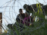 Texas troopers and guardsmen aid a migrant who got caught in concertina wire after crossing the Rio Grande from Mexico into the U.S., Tuesday, Aug. 1, 2023, in Eagle Pass, Texas.