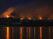 The McDougall Creek wildfire burns on the mountainside above lakefront homes in West Kelowna, Canada on Friday, Aug. 18, 2023.