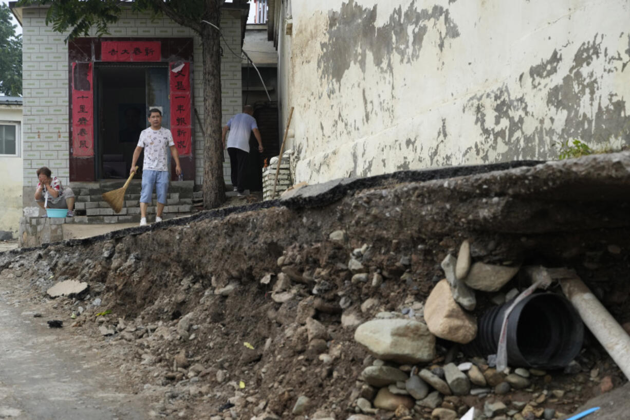 Residents try to restore normalcy to their lives near underground pipes exposed after floods sweep through a village on the outskirts of Beijing, Friday, Aug. 4, 2023. Heavy rain and high water levels on rivers in northeastern China were threatening cities downstream on Friday, prompting the evacuation of thousands, although the country appears to have averted the worst effects of the typhoon season battering parts of east Asia.