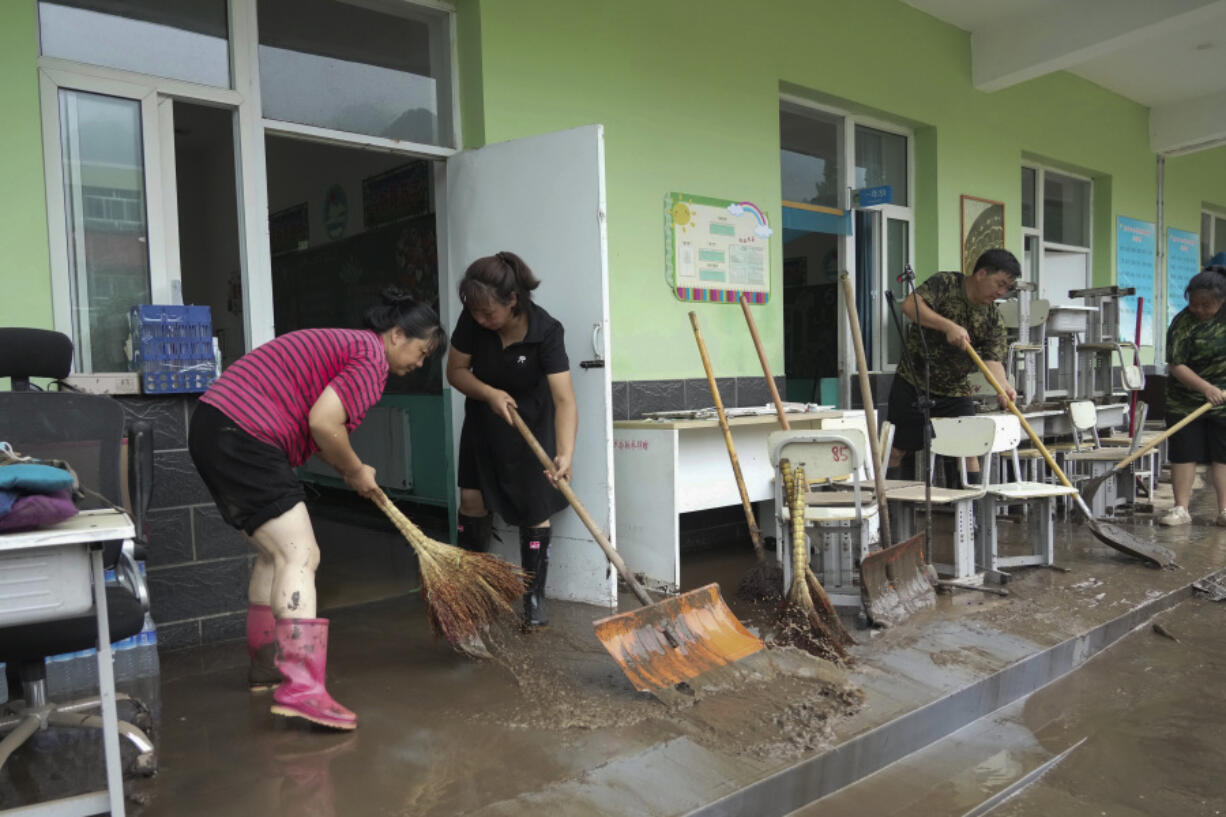 In this photo released by Xinhua News Agency, teachers clean classrooms at a school in the aftermath of flood waters from an overflowing river in Qizhongkou Town of Laishui County in north China's Hebei Province on Aug. 11, 2023. A vast swath of northeastern China is threatened by flooding as at least 90 rivers have risen above warning levels and 24 have already overflowed their banks. State media say crews are standing by to defend homes and farmland across the Songliao Basin north of Beijing which includes parts of four provinces and several major cities with a total population of almost 100 million.