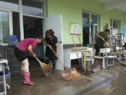 In this photo released by Xinhua News Agency, teachers clean classrooms at a school in the aftermath of flood waters from an overflowing river in Qizhongkou Town of Laishui County in north China's Hebei Province on Aug. 11, 2023. A vast swath of northeastern China is threatened by flooding as at least 90 rivers have risen above warning levels and 24 have already overflowed their banks. State media say crews are standing by to defend homes and farmland across the Songliao Basin north of Beijing which includes parts of four provinces and several major cities with a total population of almost 100 million.