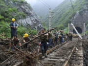 In this photo released by Xinhua News Agency, workers remove fallen debris from a railway track at a flood hit Village in Mentougou district on the outskirts of Beijing on Tuesday, Aug. 1, 2023. China's capital has recorded its heaviest rainfall in at least 140 years over the past few days after being deluged with heavy rains from the remnants of Typhoon Doksuri.