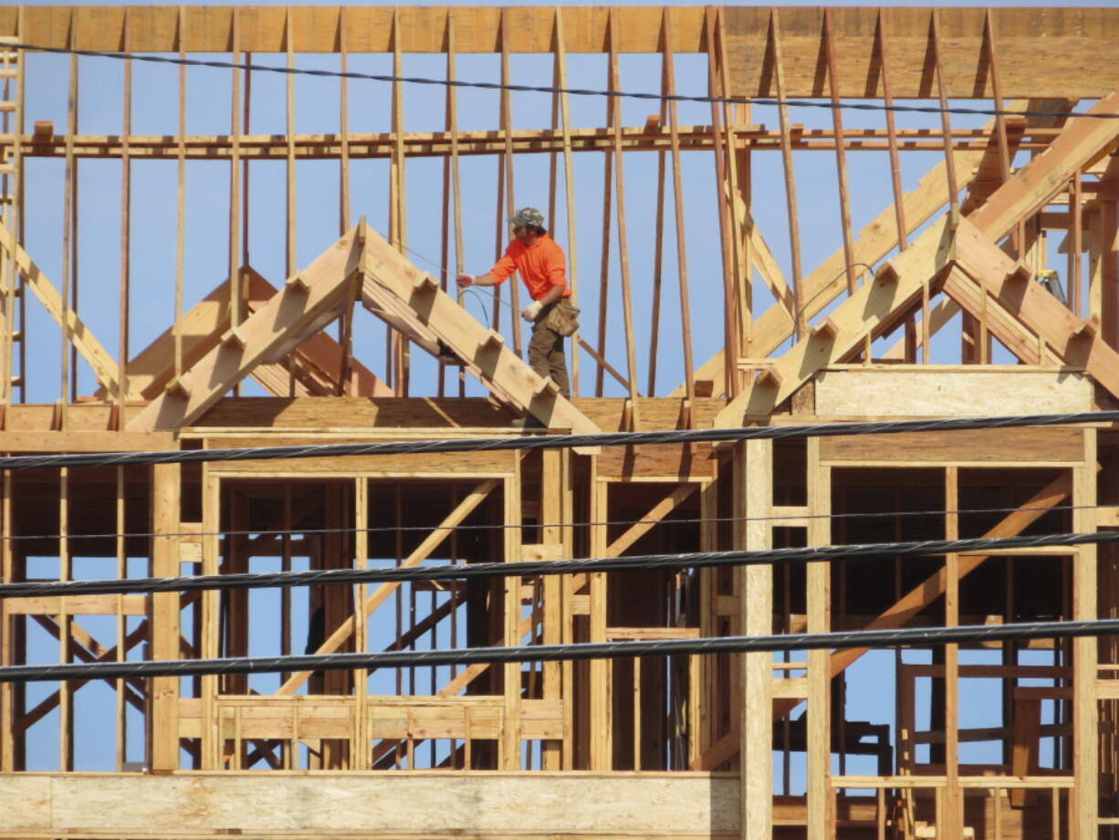 A construction worker examines part of a building under construction in Brick, N.J. on July 10, 2023. Government pushes to move buildings and vehicles away from burning fossil fuels to help address climate change are generating pu8shback in New Jersey and around the nation, with opponents worried about the cost of switching.