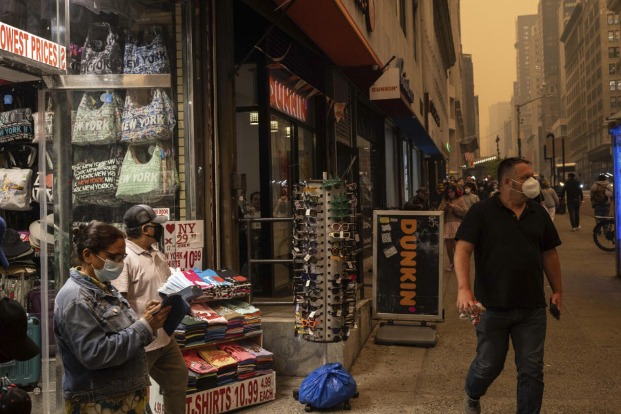 FILE - A person sells face masks outside a souvenir store in New York amid smoke from wildfires in Canada on June. 7, 2023. Across the U.S., many people are living through one of the most brutal summers of their lives and reckoning with the idea that climate change is only going to make matters worse in the coming decades.