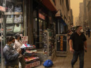 FILE - A person sells face masks outside a souvenir store in New York amid smoke from wildfires in Canada on June. 7, 2023. Across the U.S., many people are living through one of the most brutal summers of their lives and reckoning with the idea that climate change is only going to make matters worse in the coming decades.