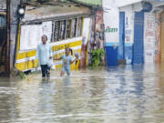 People walk through a street flooded by the rains of Tropical Storm Franklin in Santo Domingo, Dominican Republic, Tuesday, Aug. 22, 2023.