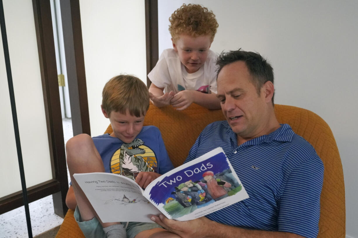 Wes Brown, right, reads to children Shawn Larimer-Brown, 7, left, and Charlie Larimer-Brown, 5, center, at their home Aug. 18 in Winter Park, Fla.